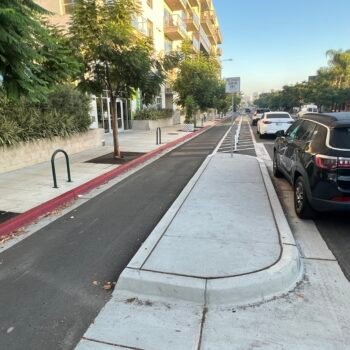 Bike lane separated from street by concrete sidewalk median.